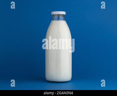 Glasmilchflasche auf blauem Hintergrund verspotten Stockfoto