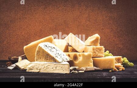 Verschiedene Käsesorten auf schwarzem Holztisch Hintergrund Stockfoto