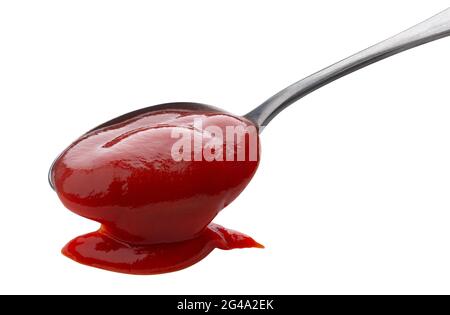Fließendes Ketchup isoliert auf weißem Hintergrund, Tomatensauce mit Metalllöffel Stockfoto