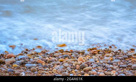 Wellen krachen auf einen Kiesstrand (langsame Verschlusszeit) Stockfoto