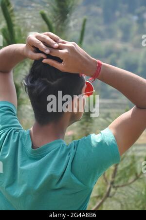 Rückansicht eines jungen Mannes, der Sonnenglas trägt und im Freien posiert Stockfoto