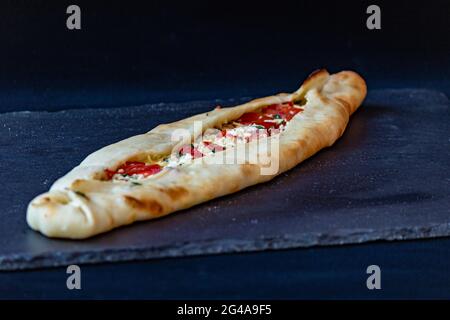 Eine Nahaufnahme eines appetitlichen Pide-Fladenbrots, gefüllt mit Tomaten, Gemüse und Käse Stockfoto