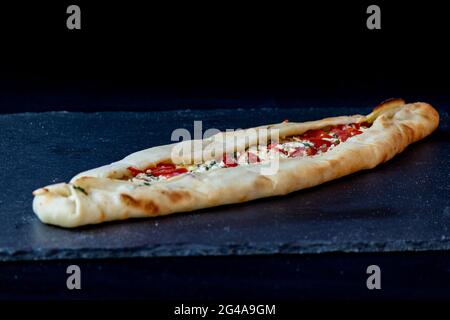 Eine Nahaufnahme eines appetitlichen Pide-Fladenbrots, gefüllt mit Tomaten, Gemüse und Käse Stockfoto