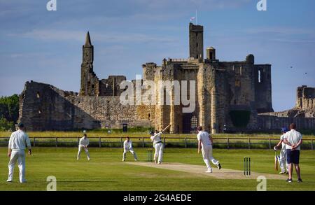 Am Samstagabend wird im Warkworth Cricket Club ein Cricket-Spiel gespielt, wobei die Ruinen des mittelalterlichen Warkworth Castle als Rückfall in Warkworth, Morpeth, Northumberland, zu sehen sind. Bilddatum: Samstag, 19. Juni 2021. Stockfoto