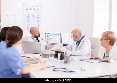 Arzt zeigt medizinische Fachvorstellung auf der Zwischenablage diskutiert Krankheitsdiagnose mit Teamarbeit bei der Gesundheitsbehandlung. Physiotherapeuten am Schreibtisch im Tagungsraum Stockfoto