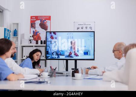 Teamarbeit bei der Diskussion über die Behandlung von Krankheiten während der telemedizinischen Online-Videokonferenz im Besprechungsraum. Ärzte erklären Krankheit Beratung Analyse der medizinischen Expertise Stockfoto