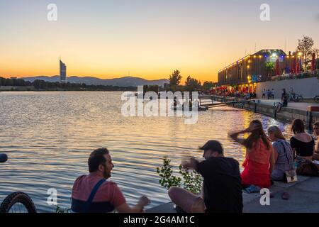 Wien, Wien: Sonnenuntergang am Copa Beach an der Neuen Donau, Menschen am Ufer, Restaurant Rembetiko, Millennium Tower 22. Donaust Stockfoto