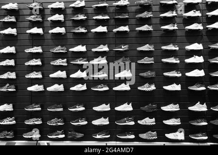 Schwarz-Weiß-Bild Shop Display von vielen Sportschuhen an der Wand. Blick auf eine Schuhwand im Laden. Moderne, neue, stylische Sneaker Laufschuhe Stockfoto