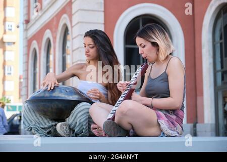 Zwei Frauen spielen eine Handpfanne und eine Melodica-Blasorgel auf der Straße. Stockfoto