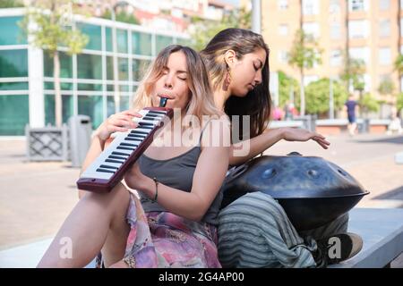 Zwei Frauen spielen eine Handpfanne und eine Melodica-Blasorgel auf der Straße. Stockfoto