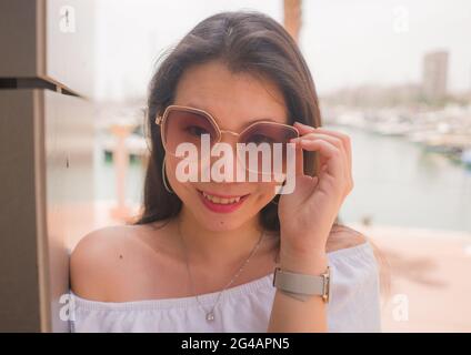 High-Key-Porträt der jungen schönen und attraktiven asiatischen japanischen Frau in kühlen Sonnenbrillen posiert im Freien an einem sonnigen Tag in Schönheit und Mode Stockfoto