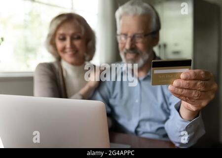 Altes Paar, das online am Computer mit Karte einkauft Stockfoto