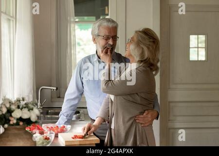 Lächelnder älterer Mann und Frau kochen zusammen zu Hause Stockfoto