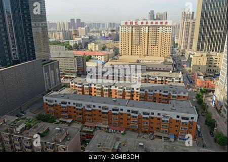 Älteres Apartmentgebäude, umgeben von neueren Apartmentgebäuden, Büros und Hotels im Zentrum von Shenyang, China Stockfoto