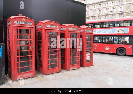 Reihe von vier roten Telefonzellen aus britischem Gusseisen, roter Londoner Bus im Hintergrund, London, England, Großbritannien Stockfoto