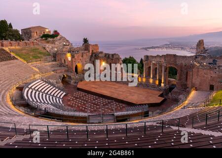 Sonnenuntergang auf dem antiken römisch-griechischen Amphitheater mit der Giardini Naxos Bucht im Hintergrund in Taormina, Sizilien, Italien Stockfoto