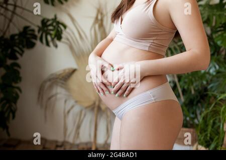 Schwangere Frau, Hände auf ihren Bauch, ein Herz Symbol Stockfoto