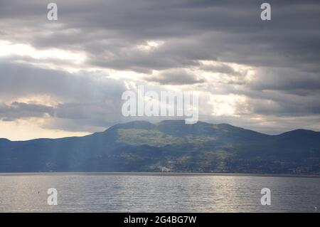 Panoramablick auf den Berg Ucka vom Meer aus. Sonnenstrahlen über Berg und Meer. Stockfoto