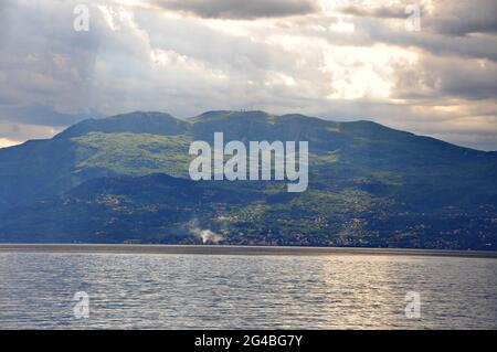 Panoramablick auf den Berg Ucka vom Meer aus. Sonnenstrahlen über Berg und Meer. Stockfoto