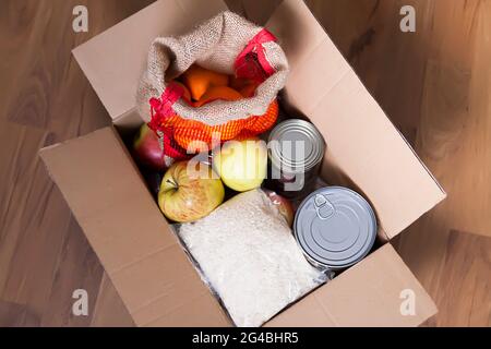 Dosen, frische Apfelfrüchte, Buchweizen und Reispackungen in einem Karton. Lebensmittelspende, Thema Lieferung. Stockfoto