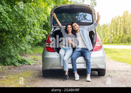 Sorgloses multirassisches Paar, das während einer Autotour Pause hat Stockfoto