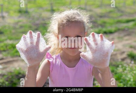 Portrait eines glücklichen kleinen Mädchens, das Hände mit Seifenschaum zeigt Stockfoto