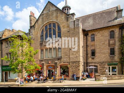 Leute, die draußen sitzen und die Sonne genießen, essen und trinken in einem Straßencafé in der Marktstadt Hexham England Stockfoto