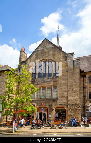 Leute, die draußen sitzen und die Sonne genießen, essen und trinken in einem Straßencafé in der Marktstadt Hexham England Stockfoto