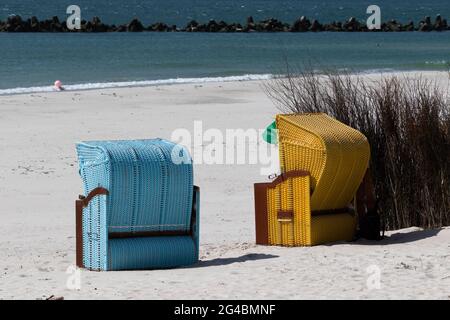 Zwei Liegestühle in gelb und blau stehen am Strand der Düne von Helgoland mit dem Meer im Hintergrund Stockfoto