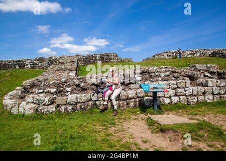 Frau hielt an, um am Milecastle 42 Cawfields zu ruhen, während sie entlang Roman baute Hadrians Wand Fernwanderweg National Trail Northumberland Stockfoto