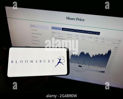 Person, die das Smartphone mit dem Logo des britischen Verlags Bloomsbury Publishing plc auf dem Bildschirm vor der Website hält. Konzentrieren Sie sich auf die Telefonanzeige. Stockfoto