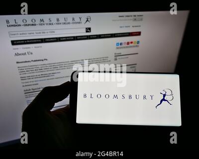 Person, die das Mobiltelefon mit dem Logo des britischen Verlags Bloomsbury Publishing plc auf dem Bildschirm vor der Unternehmenswebseite hält. Konzentrieren Sie sich auf die Telefonanzeige. Stockfoto