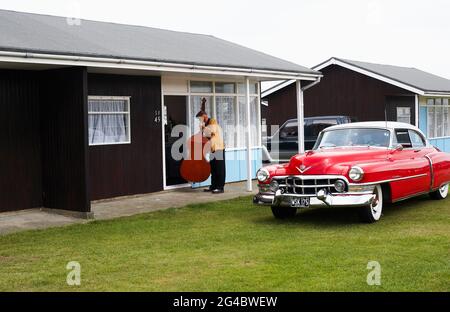 GROSSBRITANNIEN / England /Norfolk /Hemsby Rock 'N' Roll Weekender. Ein doppelter Bassist, der neben einem roten cadillac posiert. Stockfoto