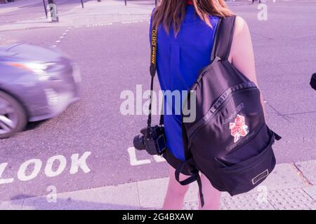 Frau in blauer Spitze trägt London 2012 Rucksack, der an Fußgängerübergangsampeln wartet, um grün zu werden, London trafalgar Square, England, Großbritannien Stockfoto