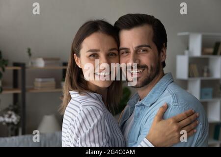 Glückliches junges liebevolles Familienpaar, das sich drinnen umarmt. Stockfoto