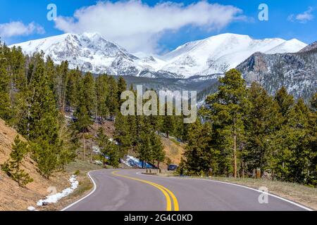 Spring Mountain Road - Blick auf die verwinkelte Fall River Road mit schneebedeckter Mummy Range im Hintergrund, Rocky Mountain National Park. Stockfoto