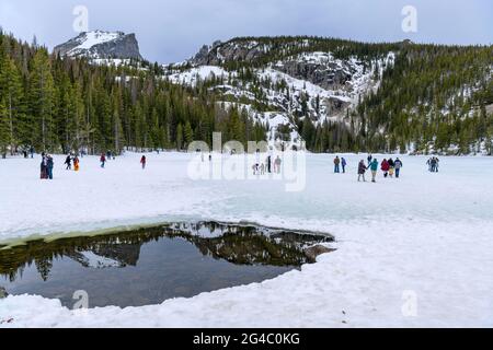 Frühling am Bear Lake - Es ist Frühling; Touristen genießen es auf dem noch gefrorenen und schneebedeckten Bear Lake im Rocky Mountain National Park, CO, USA. Stockfoto