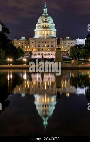 Das Kapitol bei Nacht - EINE vertikale Sicht auf die Westseite des US-Kapitolgebäudes bei Nacht mit einem Sommerkonzert vorne, das sich im Reflecting Pool, USA, widerspiegelt. Stockfoto