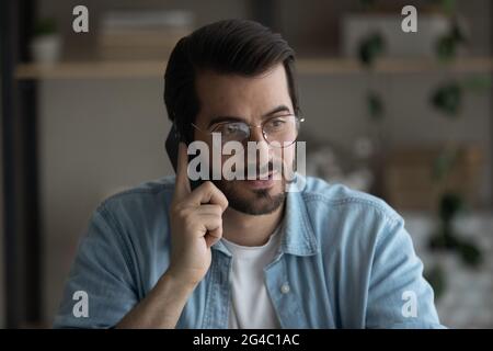 Lächelnder junger Mann hält Telefonanruf in der Halle. Stockfoto
