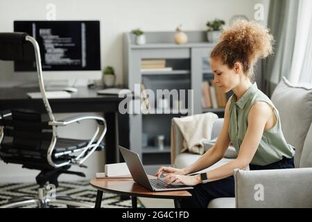 Geschäftsfrau sitzt auf dem Sofa und arbeitet an ihrem Laptop, sie arbeitet von zu Hause aus Stockfoto