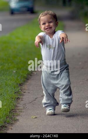 Glücklicher kleiner Kleinkind Junge, der seine ersten Schritte im Freien macht Stockfoto