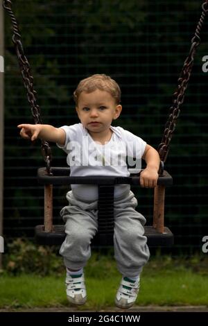 Kleiner Kleinkind Junge auf Schaukel im Park zeigt Stockfoto