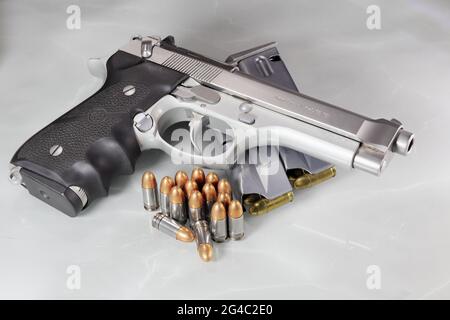 Beretta 92FS oder M9 Handfeuerwaffe und Paket von Kugeln 9mm Parabellum isoliert auf Reflexionsfläche Stockfoto