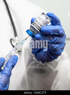 Corona-Virus-Impfstoff in Arzthänden hält der Arzt in Weiß eine Spritze und eine COVID-19-Impfstoffflasche zur Injektion. Konzept der Impfstoffimpfung, Immunisierung Stockfoto