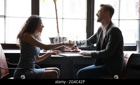 Glückliche junge afrikanische Frau, die dem Mann die Hände schüttelt. Stockfoto