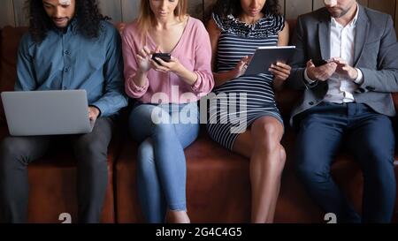 Vier verschiedene junge Menschen mit verschiedenen Gadgets. Stockfoto