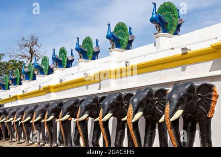 Reihe von Pfau- und Elefantenstatuen in der Hofmauer des Kataragama-Tempels in Sri Lanka. Stockfoto