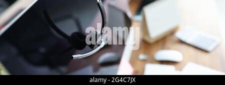 Kopfhörer mit Mikrofon, das in Nahaufnahme am Computermonitor aufgehängt wird Stockfoto