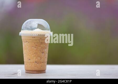 Kaffeeshakes werden auf einem Holztisch im Blumengarten platziert. Stockfoto