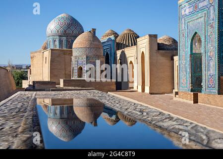 Mausoleen und Kuppeln des historischen Friedhofs von Shahi Zinda und ihre Reflexionen in Pfützen, Samarkand, Usbekistan. Stockfoto